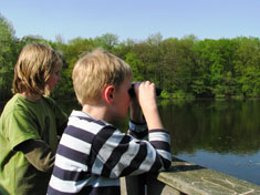 Kinder beobachten mit einem Fernglas Tiere am Wasser. Foto: Dr. G. Hein, NUA