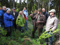 Geprüfter Natur- und Landschaftsführerin führt eine Gruppe im Wald. Foto: Dr. G. Hein; NUA